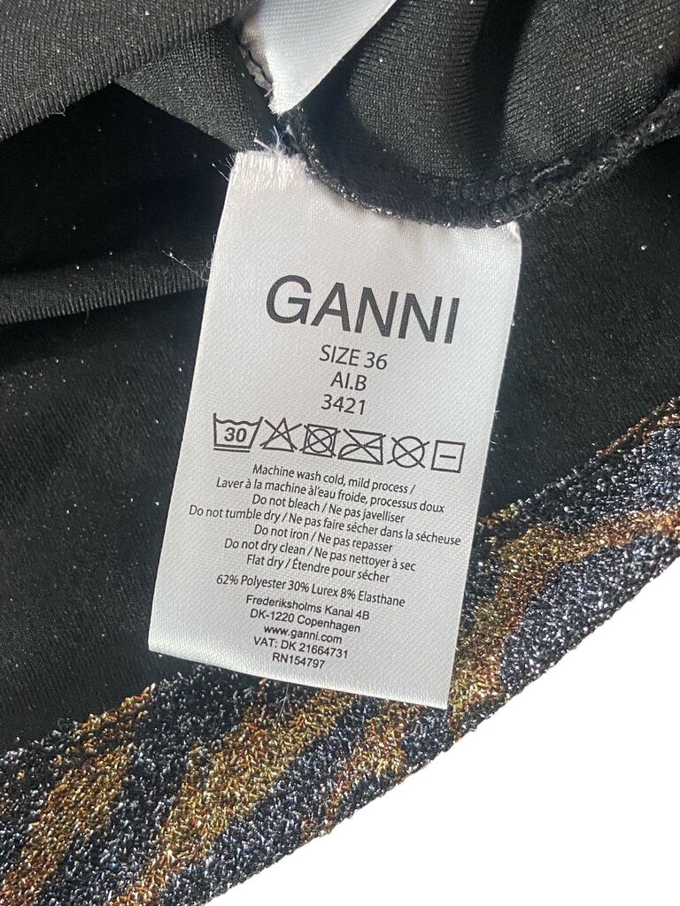 The Ganni Lurex Tiger Print Stretch Top is a bold, statement-making piece that combines shimmering lurex fabric with an eye-catching tiger print for a fierce yet elegant look. Its form-fitting design and stretchy material offer comfort while adding a touch of wild sophistication to any outfit.