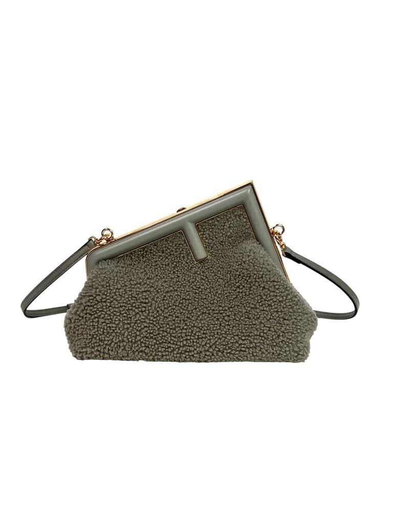 The Fendi First Shearling Bag is a luxurious and cozy handbag crafted from plush shearling, combining softness with high-fashion appeal. Its distinctive "F" clasp and sleek, compact silhouette make it a statement piece for both casual and evening looks.